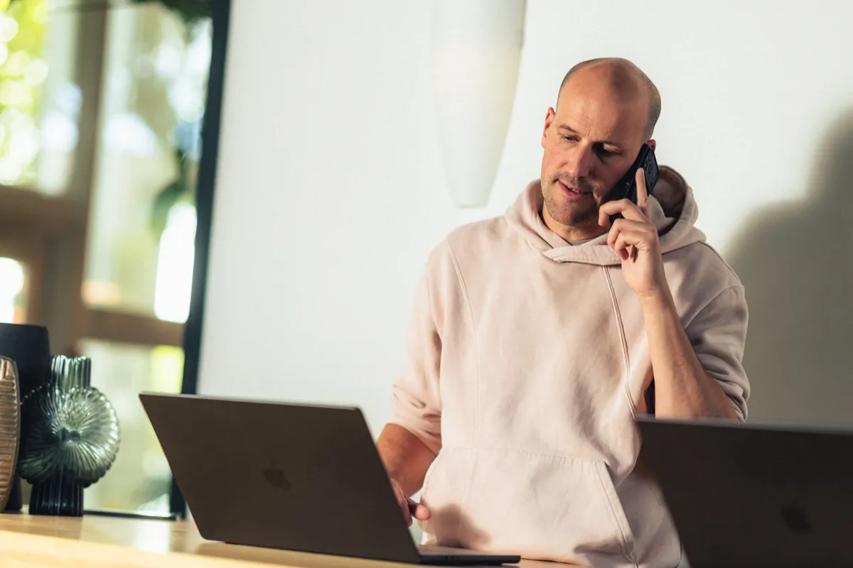 Codeforward-consultant helpt een klant aan de telefoon achter zijn laptop